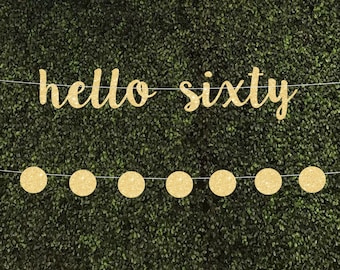May include: Gold glitter banner with the text "hello sixty" and a string of gold glitter circles.