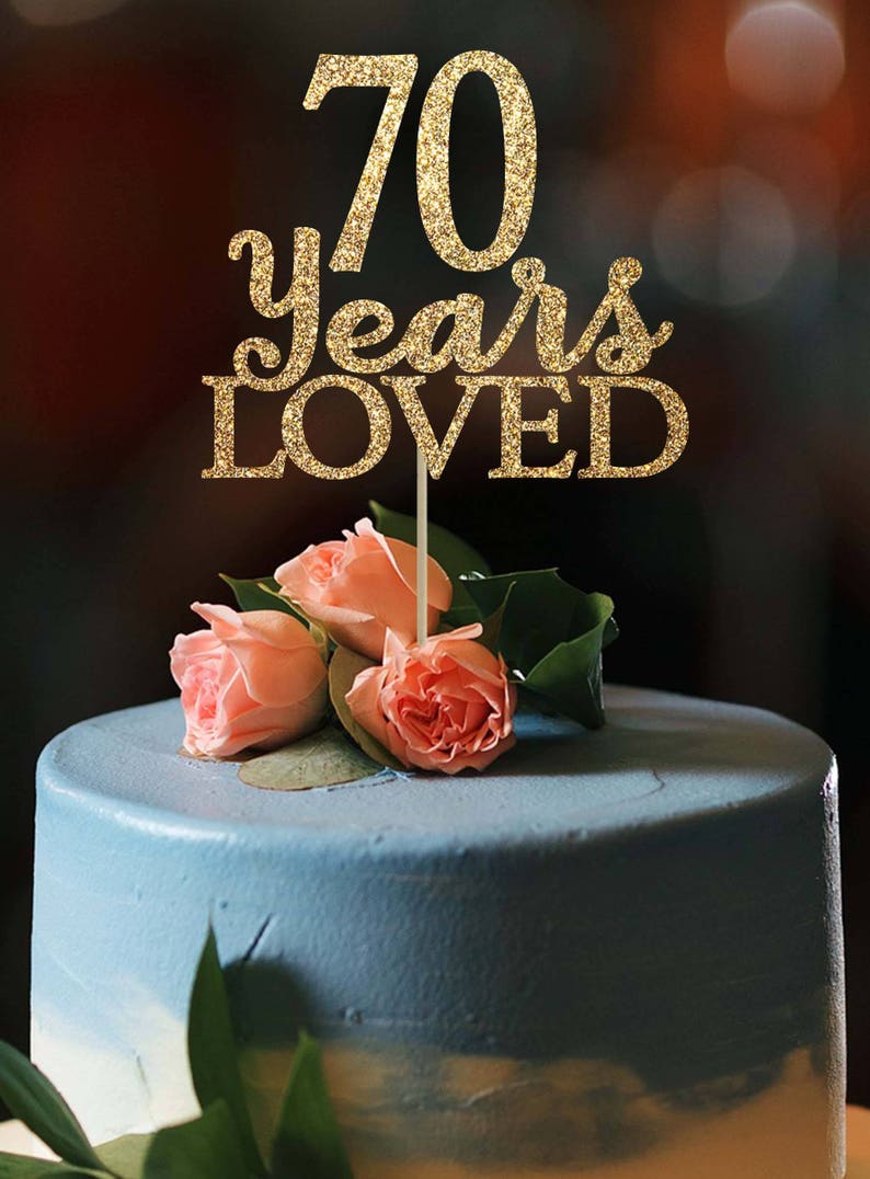 May include: Gold glitter cake topper with the text "70 years loved".