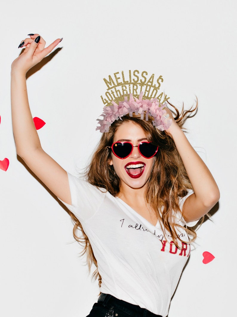 May include: A woman wearing a white t-shirt with the text "I already love you" and a gold glitter headband that says "Melissa's 40th Birthday".