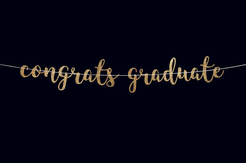 Peut inclure: Banni&egrave;re dor&eacute;e &agrave; paillettes avec le texte "Congrats Graduate" suspendue &agrave; une ficelle blanche sur un fond noir.