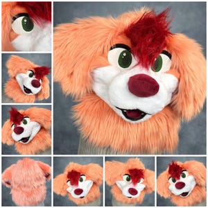 May include: A plush animal head mask featuring long peach-colored faux fur, a white muzzle, and a deep red tuft of hair on the forehead. The mask has large green eyes with black pupils, a dark red nose, and an open mouth showing dark interior.