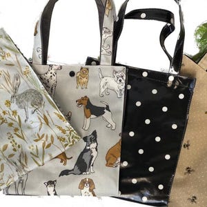 Peut inclure: Quatre sacs fourre-tout avec diff&eacute;rents motifs. L'un pr&eacute;sente un motif de lapin et de plantes sur fond clair. Un autre a un motif de chien. Le troisi&egrave;me sac est noir avec des pois blancs. Le dernier sac est beige avec un motif d'abeilles.