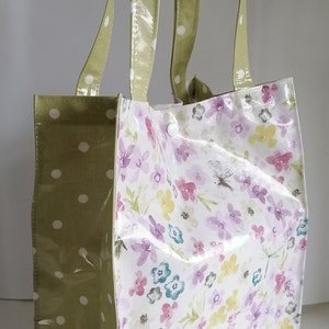 Peut inclure: Un sac fourre-tout &agrave; motifs floraux et &agrave; pois verts. Le sac pr&eacute;sente un fond blanc avec des fleurs violettes, roses et jaunes. Les poign&eacute;es et un c&ocirc;t&eacute; du sac sont vert olive avec des pois blancs. Fermeture &agrave; bouton-pression blanche.