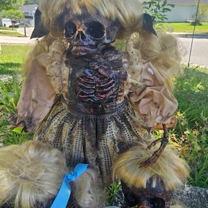 May include: Three creepy porcelain dolls with realistic painted faces and hair. The dolls are dressed in vintage-style clothing. The doll in the center is wearing a brown dress with a black bodice and a white lace collar. The dolls on either side are wearing white dresses with floral patterns. The dolls are all in various states of decay, with cracked paint and missing limbs.