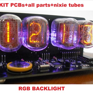 May include: A black electronic clock with four Nixie tubes displaying the time. The tubes glow with orange digits and are surrounded by a purple backlight. The text "KIT PCBs+all parts+nixie tubes" and "RGB BACKLIGHT" are visible.