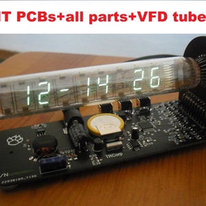 Puede incluir: Un kit de reloj digital con un tubo VFD que muestra 12:14:26. El reloj está construido sobre una placa de circuito negro con varios componentes electrónicos. El texto "KIT PCBs+all parts+VFD tube" es visible.