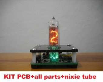 May include: A Nixie tube display kit with a glowing orange number 2 inside a glass tube. The tube is mounted on a black platform with a green circuit board base. The text "KIT PCB+all parts+nixie tube" is at the bottom.