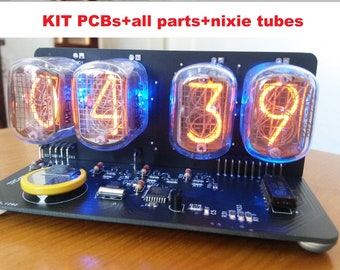 May include: A Nixie tube clock kit with the text "KIT PCBs+all parts+nixie tubes". The clock features four glowing orange digits inside glass tubes, mounted on a black circuit board. The tubes are lit with a blue glow.