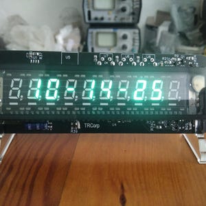 May include: A black digital display with bright green numbers, mounted on clear acrylic legs. The display shows the numbers 8.8.8.8.8.8.8.8. The device has a black frame and the text "TRCorp" is visible.