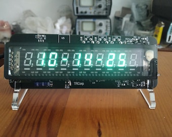 May include: A black digital display with bright green numbers, mounted on clear acrylic legs. The display shows the numbers 8.8.8.8.8.8.8.8. The device has a black frame and the text "TRCorp" is visible.