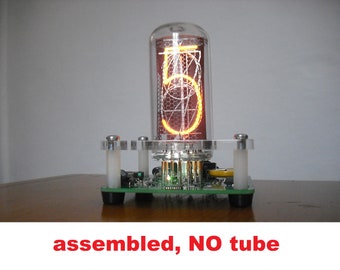 May include: An assembled Nixie tube clock component with a glowing orange number 5 displayed inside a glass tube. The base is green with electronic components and clear acrylic supports. The text "assembled, NO tube" is at the bottom.