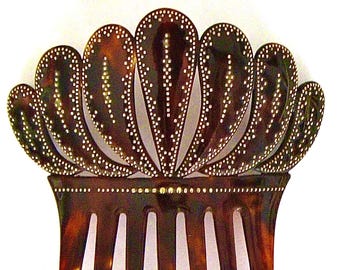 May include: A tortoiseshell hair comb with a decorative top made of overlapping, scalloped shapes. The top is decorated with small, gold-colored dots.