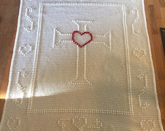May include: A white crocheted blanket with a red heart in the center of a white cross design.