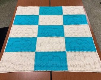 May include: A crocheted baby blanket with a checkered pattern of white and turquoise squares. Each square features a repeating design of small circles.