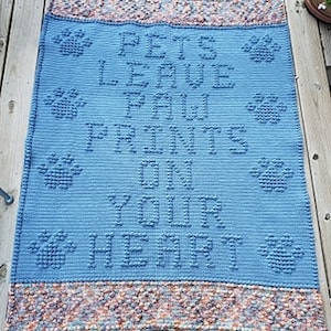 Può includere: Coperta all'uncinetto blu con un design a forma di impronta di zampa bianca e il testo "Pets Leave Paw Prints On Your Heart".