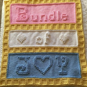 Puede incluir: Una manta de bebé de crochet con un borde amarillo y tres paneles. El panel superior es rosa y dice "Bundle of", el panel del medio es blanco y tiene una huella y un corazón, y el panel inferior es azul y dice "Love".