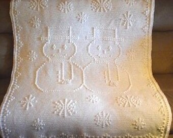 May include: White crocheted blanket with two snowmen and snowflake designs.