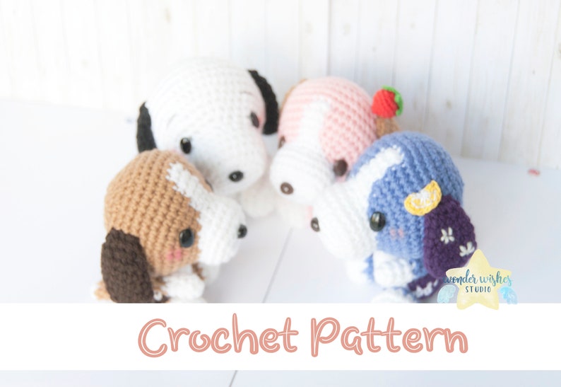 Pode incluir: Quatro c&atilde;es de peluche de croch&ecirc; em diferentes cores. Os c&atilde;es s&atilde;o branco, castanho, rosa e azul. O c&atilde;o branco tem orelhas pretas. O c&atilde;o castanho tem marcas brancas. O c&atilde;o rosa tem um morango vermelho na cabe&ccedil;a. O c&atilde;o azul tem um lim&atilde;o amarelo e flores roxas no corpo. O texto "Crochet Pattern" est&aacute; na parte inferior da imagem.