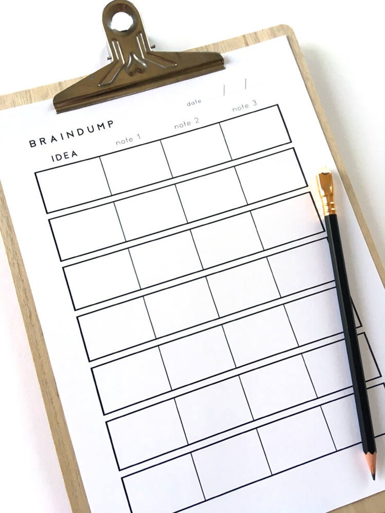 May include: A white clipboard with a wooden frame and a silver clip. The clipboard has a grid of boxes labeled "note 1", "note 2", "note 3", and "date". The clipboard is on a white surface with a black pencil.