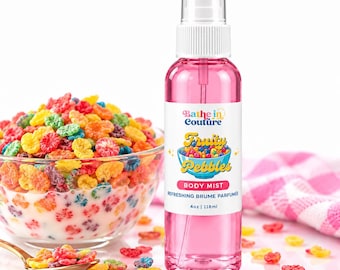 May include: A clear plastic spray bottle filled with pink liquid, labeled Bathe in Couture Fruity Pebbles Body Mist, 4oz | 118ml. The label features a bowl of colorful cereal. Beside it sits a glass bowl filled with milk and colorful cereal.