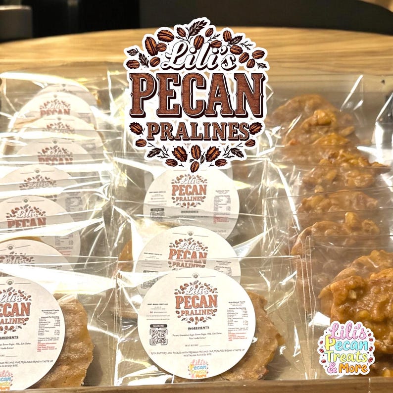 May include: Multiple individually wrapped pecan pralines in clear plastic bags. Each package features a round white label with the text Lili's PECAN PRALINES, ingredient lists, and a QR code. A large logo with the same text sits above.