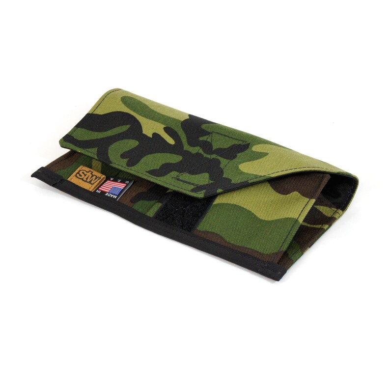 Op de afbeelding: Een camouflage-portemonnee met een zwarte band en een klein Amerikaans vlaglabel met de tekst "Made in USA".