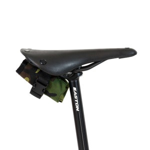 Op de afbeelding: Een zwart zadel voor een fiets met een camouflage zadeltas bevestigd aan de zadelpen. De zadelpen is gemarkeerd met "EASTON".