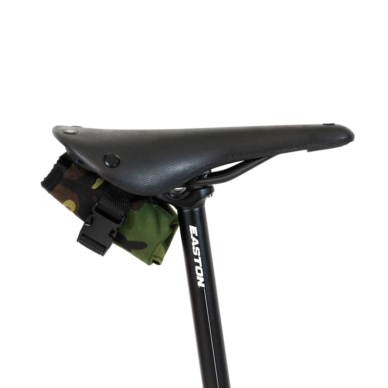 Op de afbeelding: Een zwart zadel voor een fiets met een camouflage zadeltas bevestigd aan de zadelpen. De zadelpen is gemarkeerd met "EASTON".
