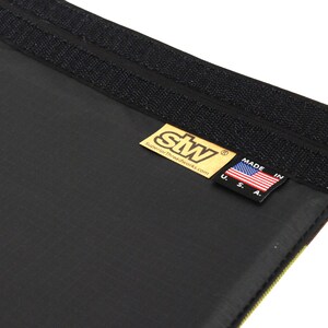 Puede incluir: Primer plano de una tela negra con una etiqueta dorada que dice "stw SuperiorThreadworks.com" y una peque&ntilde;a bandera estadounidense con el texto "Made in U.S.A."