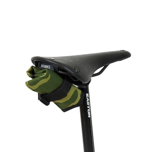 Op de afbeelding: Een zwart Brooks-zadel met een groene en bruine camouflage zadeltas die aan de onderkant is bevestigd. Het zadel is gemonteerd op een zwarte Easton zadelpen.