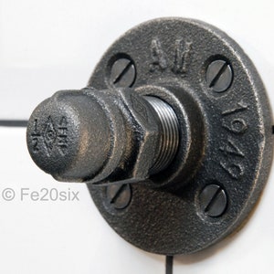 May include: A black metal pipe flange with a threaded pipe fitting and a black metal cap. The flange has the text "1/2" and "1947" on it.