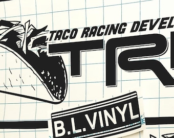 Könnte beinhalten: Schwarz-weißer Aufkleber mit dem Text "Taco Racing Development TRD" und einem Cartoon-Bild eines Tacos. Der Aufkleber enthält auch den Text "B.L. Vinyl".