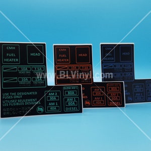 May include: A set of six black fuse box labels with white and red text. The labels are for a car's electrical system and include fuses for the headlamps, charge, hazard horn, fuel heater, glow plugs, and diesel engine. The labels are printed with the text "CMH", "FUEL HEATER", "HEAD", "GLOW AM 1", "AM 2", "AM 1", "80A", "60A", "40A", "DIESEL", "10A", "7.5A", "15A", "HEAD (RH)", "HEAD (LH)", "HEAD (LM)", "CHARGE", "HAZ HORN", "SNES", "NT", "ED", "IT", "D", "USE THE DESIGNATED FUSES ONLY", "UTILISEZ SEULEMENT LES FUSIBLES DESIGNES.", "指定のヒュース以外 使用しないで下さい".