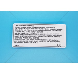 May include: A blue and white maintenance sticker with the text "Air Cleaner Service", "Engine Oil & Oil Filter Service", "Supercharger Oil Service", and "C6". The sticker provides instructions for replacing air filters, engine oil, and oil filters, and inspecting the oil level in a supercharger.