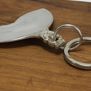 May include: A silver heart-shaped keychain with an ornate design and a silver key ring.