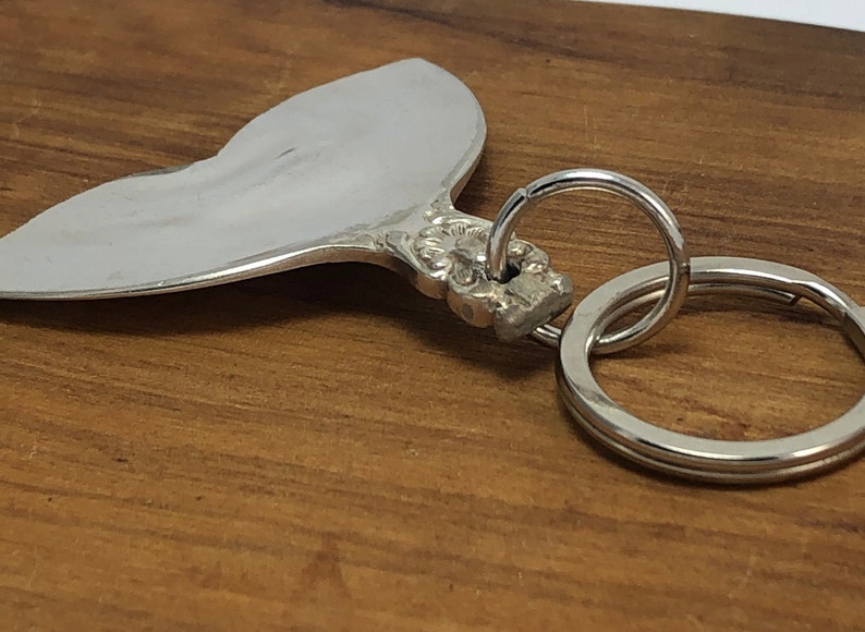 May include: A silver heart-shaped keychain with an ornate design and a silver key ring.