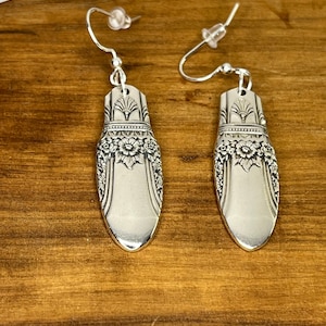 Peut inclure: Une paire de boucles d'oreilles en argent fabriquées à partir d'argenterie vintage. Les boucles d'oreilles présentent un motif floral et sont suspendues à des crochets en argent.