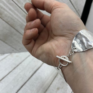 A hand with the bracelet hanging nicely on it showing the beautiful toggle clasp.