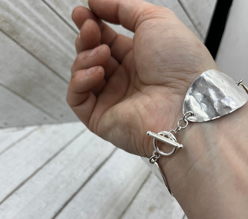 A hand with the bracelet hanging nicely on it showing the beautiful toggle clasp.