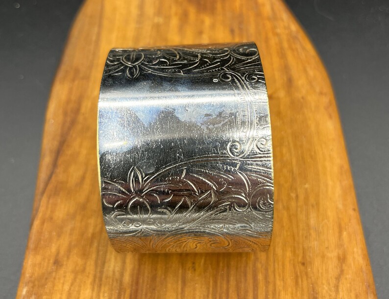May include: Silver napkin ring with an ornate floral design.