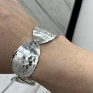 Wrist with the textured spoon bowl bracelet on it, showing off it's beautiful texture and shine.