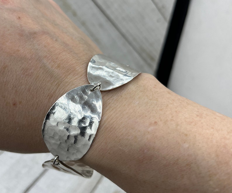 Wrist with the textured spoon bowl bracelet on it, showing off it's beautiful texture and shine.