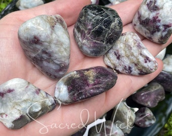 May include: A collection of tumbled stones with white, pink, and black markings. The stones are smooth and polished, and they have a variety of shapes and sizes.