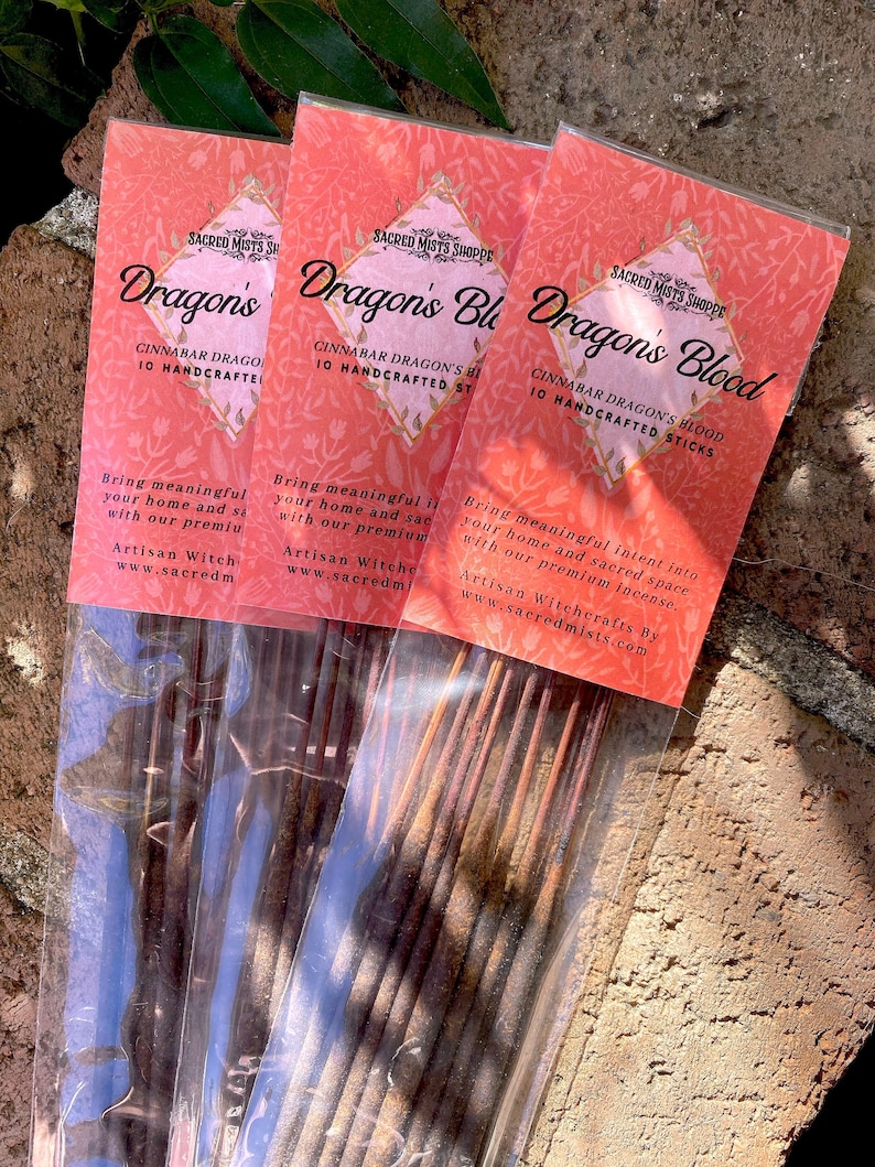 Three packages of Dragon's Blood Stick Incense is lying on bricks with nearby leaves.