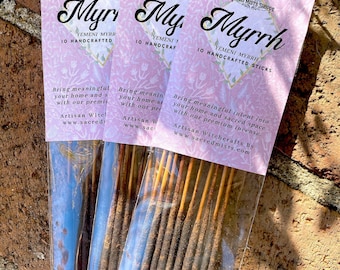 May include: A pack of 10 hand-crafted Yemeni Myrrh incense sticks. The packaging is pink with a floral pattern and the text "Sacred Mists Shoppe" and "Yemeni Myrrh 10 Handcrafted Sticks".