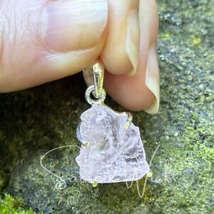 aa+ quality pink kunzite raw nugget set in sterling silver being held with fingers to show details of the stone's natural texture and approximate size
