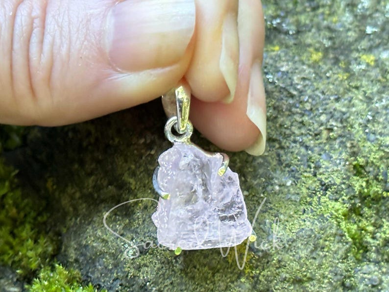 aa+ quality pink kunzite raw nugget set in sterling silver being held with fingers to show details of the stone's natural texture and approximate size