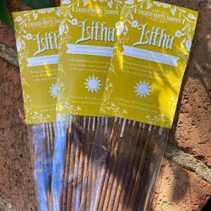 May include: Three packages of incense sticks with yellow labels that say "Sacred Mists Shoppe" and "Litha Sunflowers & Peony 10 Handcrafted Sticks". The labels also include the text "Bring meaningful intent into your home and sacred space with our premium incense."  Artisan Witchcrafts By www.sacredmists.com
