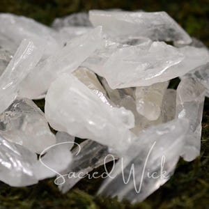 Puede incluir: Una colección de puntas de cristal de cuarzo transparente, también conocidas como cristales de roca, sobre un lecho de musgo verde. Los cristales son de varios tamaños y formas, algunos tienen una punta puntiaguda y otros son más redondeados.