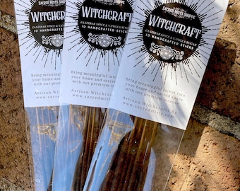 May include: Three packs of incense sticks labelled "Witchcraft" with the text "Zanzibar Spice & Vanilla Sugar 10 Handcrafted Sticks". The packs are on a brick surface.
